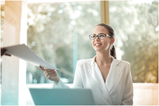 A woman is handing over documents to a person