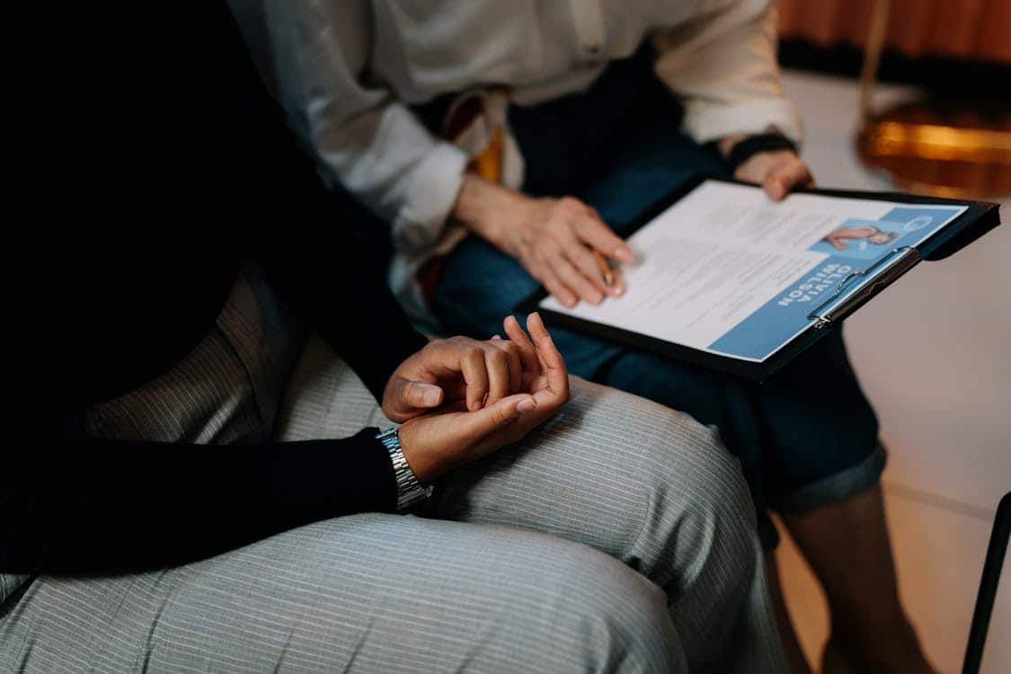 Two people holding a clipboard with a resume 