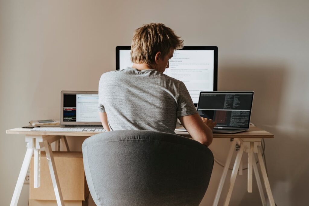 Man coding on multiple screens at a home office.