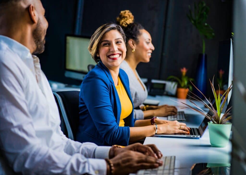 Happy diverse team working together at computers