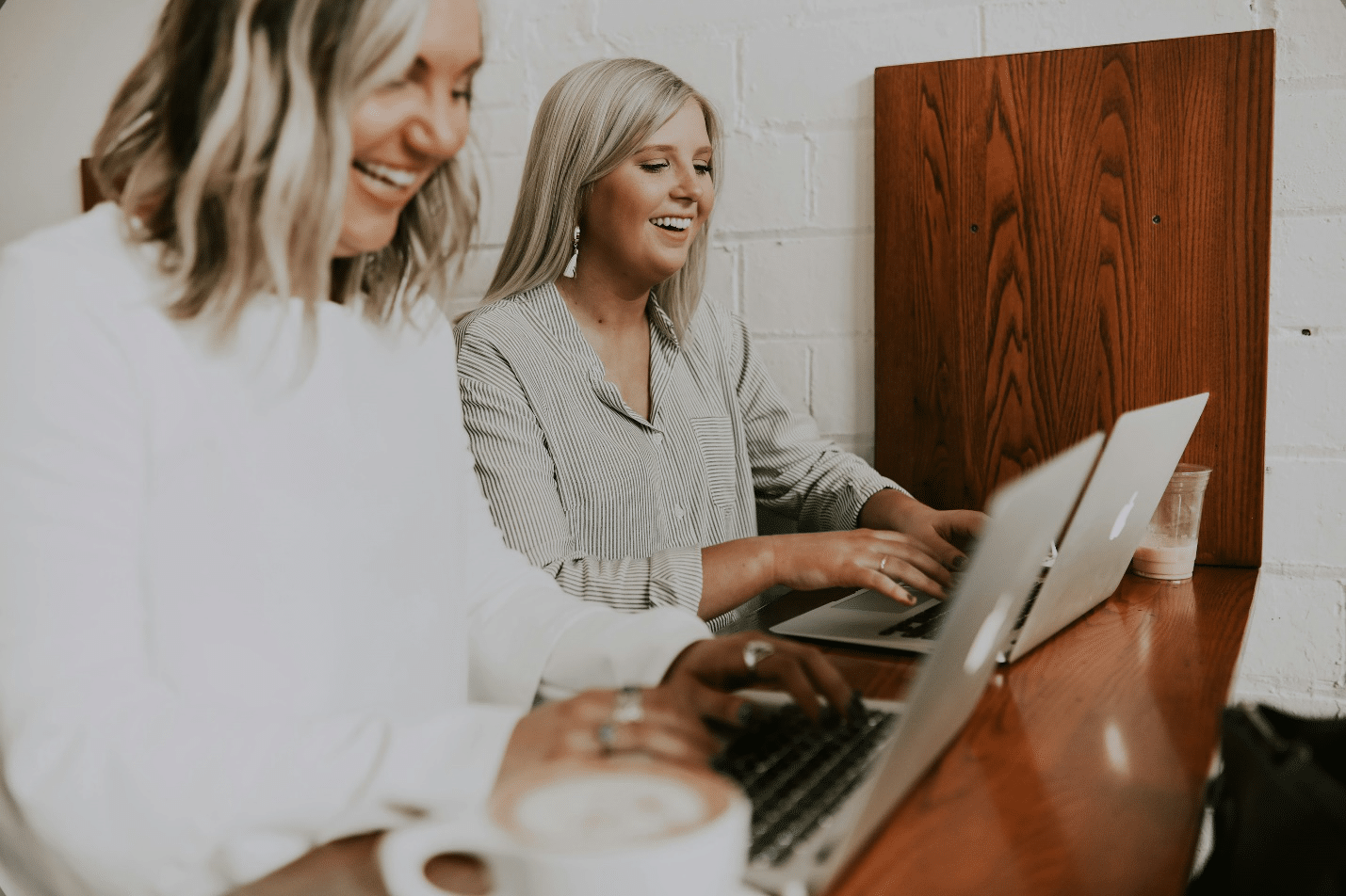 Two women working on laptops at a shared desk