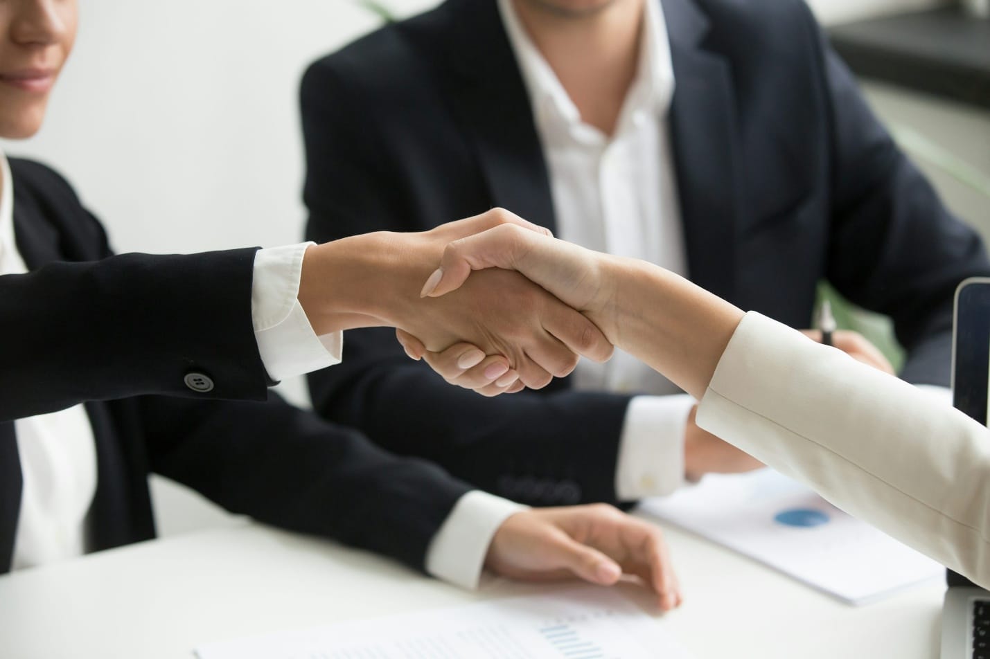Business professionals shaking hands after completing compliance review