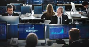 Financial professionals working in an office setting with compliance data on screens