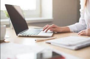 a person using a computer on a wooden desk.
